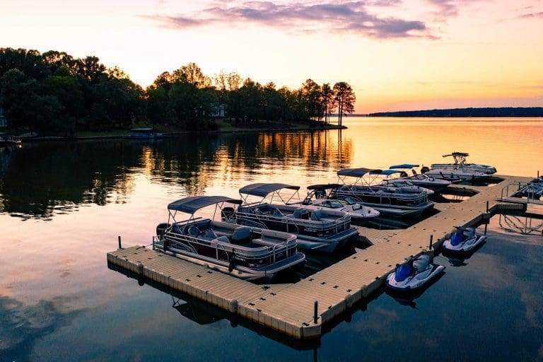 a collection of boats and jet-skis at the docks at sunset